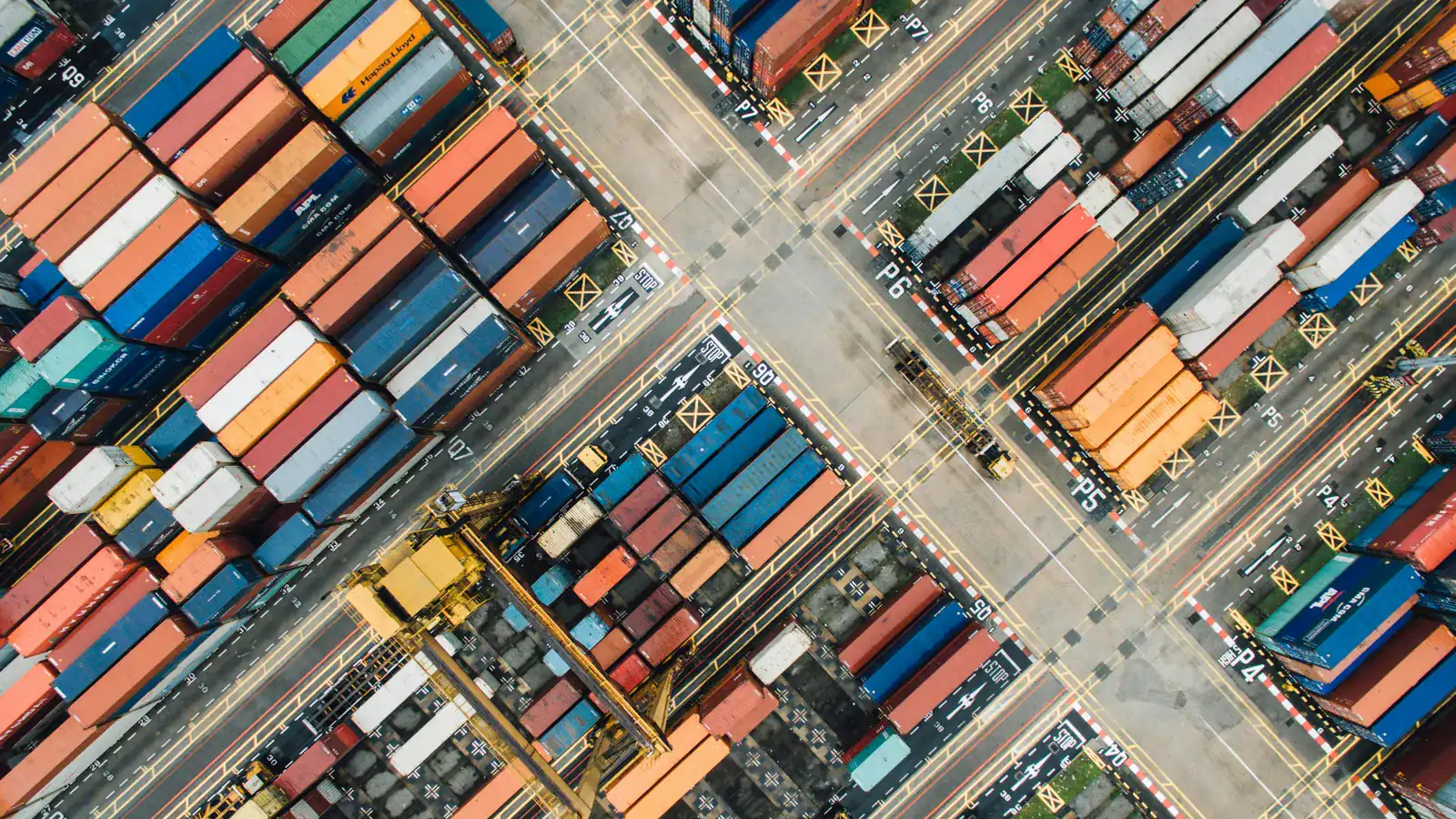 Aerial view of a shipping container port with stacked containers and cranes