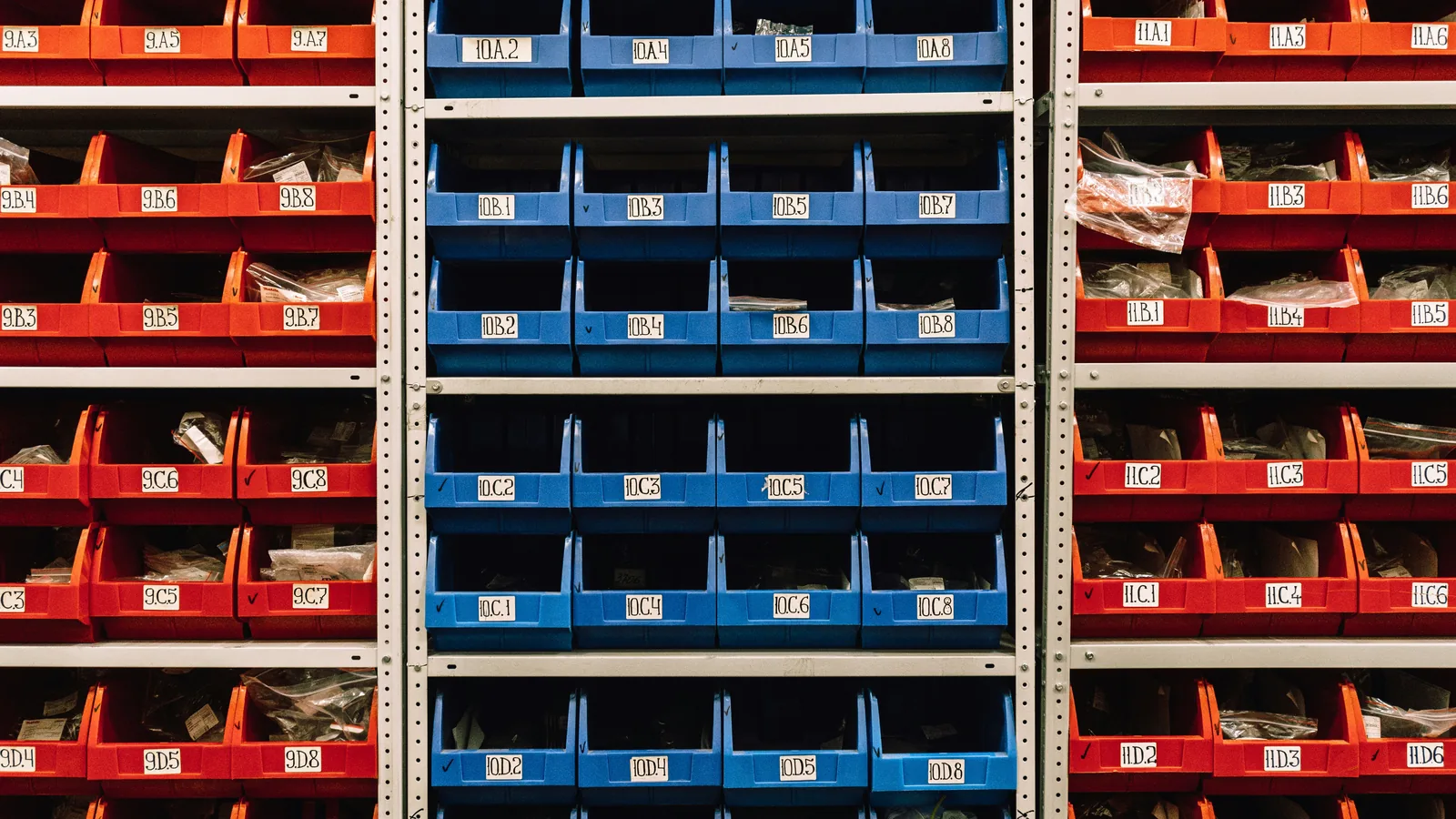 Racks of neatly organized red, blue and orange storage bins