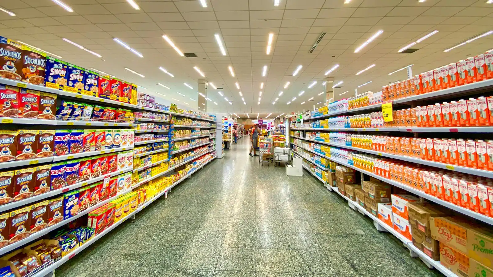 Fully stocked supermarket aisle with cereal and milk shelves and restock cases on the floor