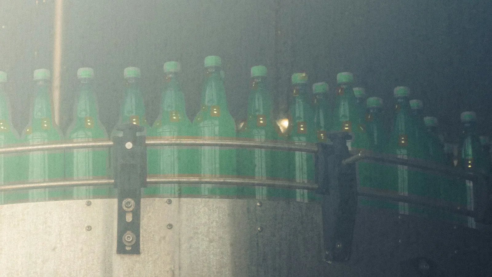 Green bottles moving along a bottling line conveyor