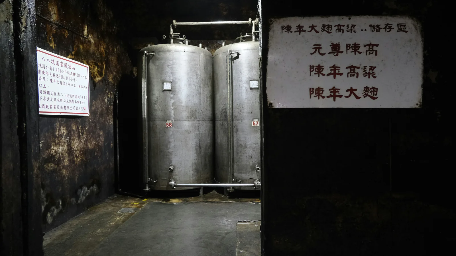 Two large stainless steel tanks in a dark production room