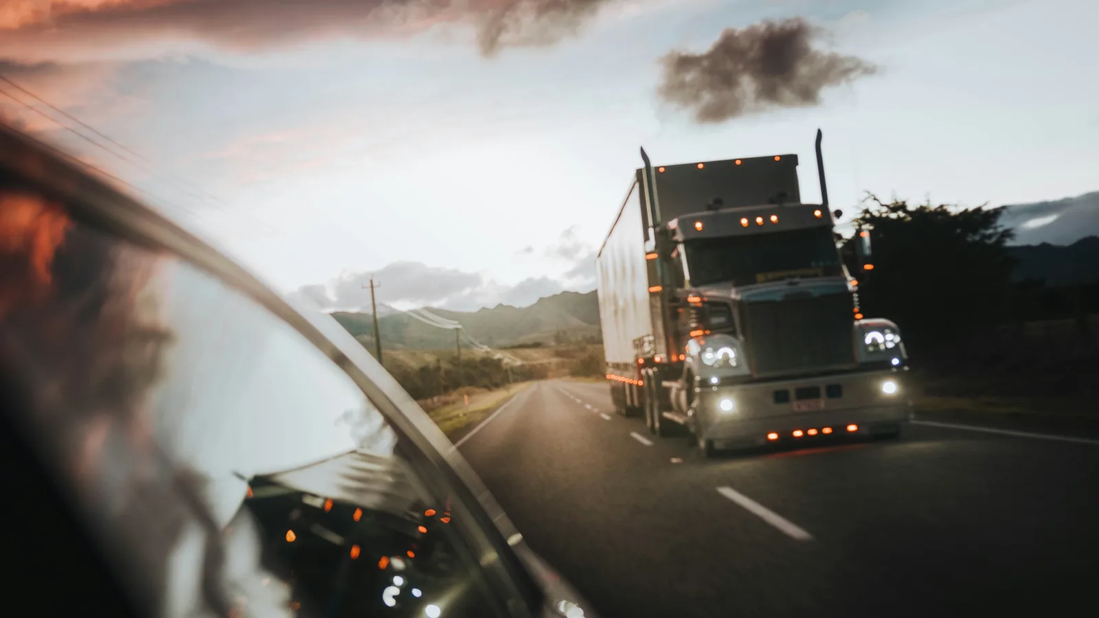 Semi truck driving on a highway at dusk