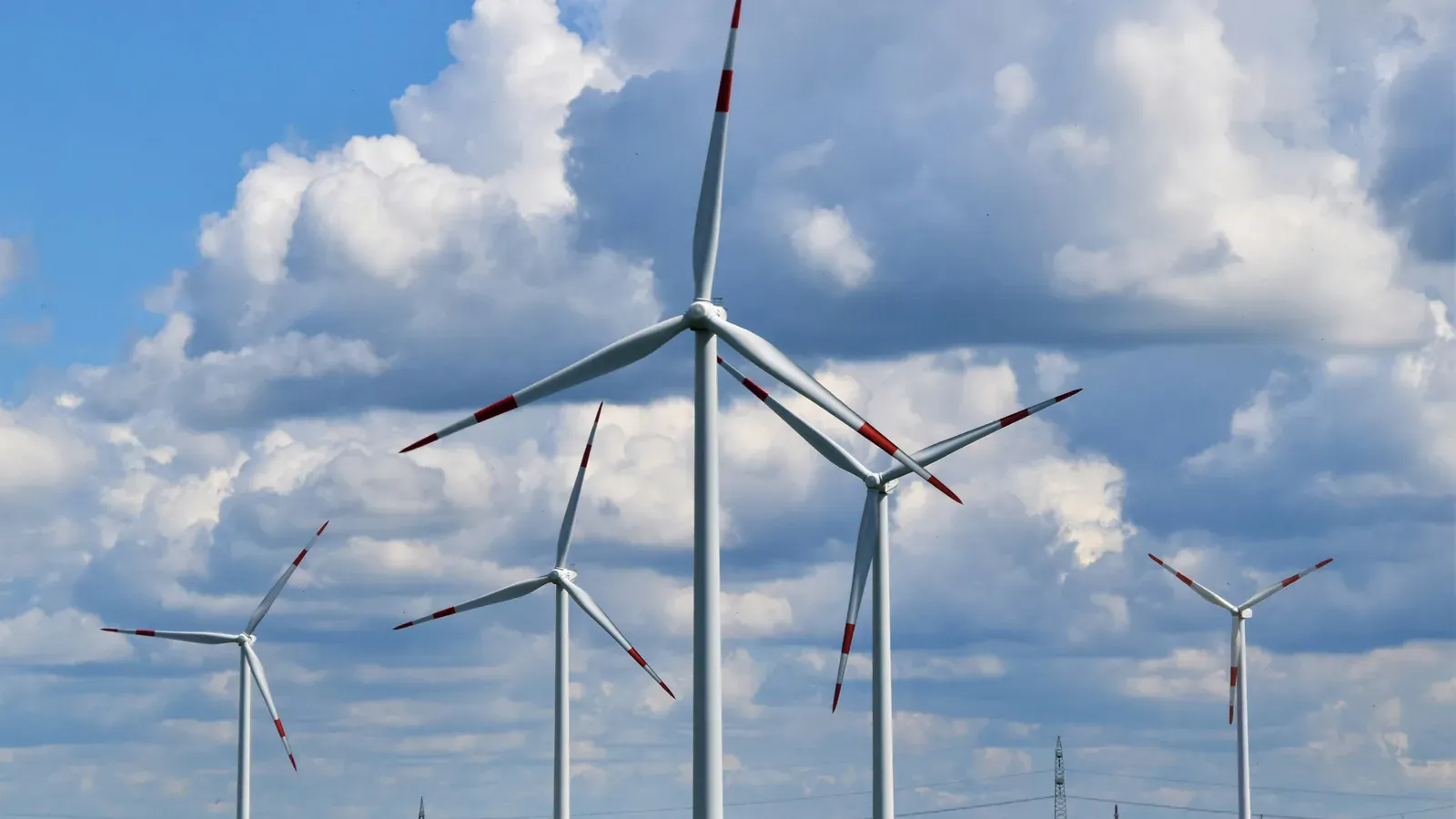 Wind turbines on a green field under a cloudy sky